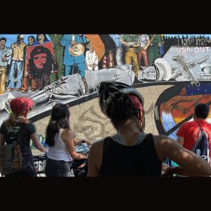 bike riders in front of che guevara mural